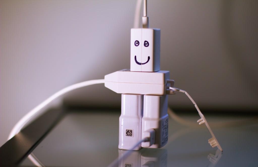 Valkoisia sähköpistokkeita, jotka yhdessä muodostavat hymyilevän robotin
