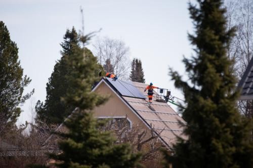 Työntekijöitä katolla asentamassa aurinkopaneeleita.