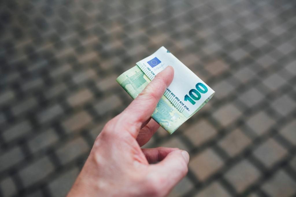 Käsi ojentaa 100 euron seteliä
